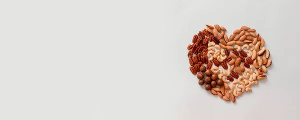 Top view of assorted love shape nuts on gray background with copy space on gray background — Stock Photo, Image