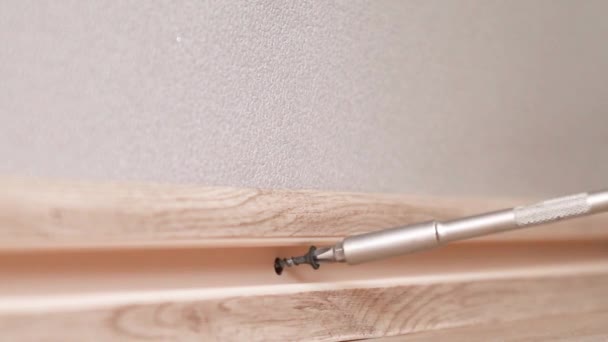 Human hand touches the plastic baseboard with a screwdriver and dowel. Installation and installation of plastic floor plinth — Stock Footage Human hand touches the plastic baseboard with a screwdriver and dowel. Installation and installation of plastic floor plinth Video Clip