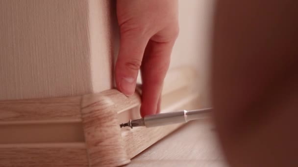 Human hand touches the plastic baseboard with a screwdriver and dowel. Installation and installation of plastic floor plinth — Stock Footage Human hand touches the plastic baseboard with a screwdriver and dowel. Installation and installation of plastic floor plinth Video Clip