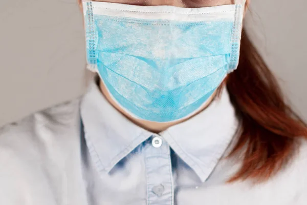 Girl in a medical mask on grey background. Protection against diseases, epidemics and viruses. Coronavirus, covid 19