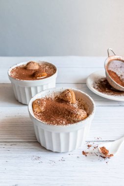 Klasik tiramisu tatlısı gri arka planda beyaz kavanozda