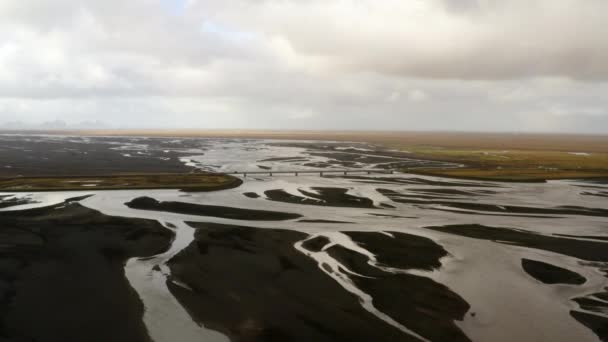 从空中俯瞰三角洲 冰岛南部的黑色火山灰 过桥的汽车 冰川河流 绿色平原 多云的白昼 — 图库视频影像