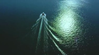 Su yüzeyindeki sürat teknesini izleyen kamera, yukarıdan dikiz manzaralı. Denizde seyreden lüks motorlu tekne, yelkenli tekneler..