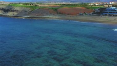 Gran Canaria 'nın hava manzarası, bulutlu, palmiyeli, lüks tatil beldeleri ve uzak dağları olan güzel sahil manzarası..