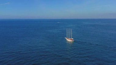Yalnız Yelkenli Tekne 'nin hava manzarası, okyanusta tuvali olan bir geminin drone görüntüsü. Okyanusun ortasında uçan bir gemi. Tahta direk.