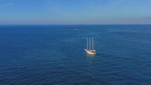 ロンリーセーリングボートの空中ビュー 海にキャンバス付きの船のドローンビュー 海の真ん中を流れる船 木造マスト — ストック動画