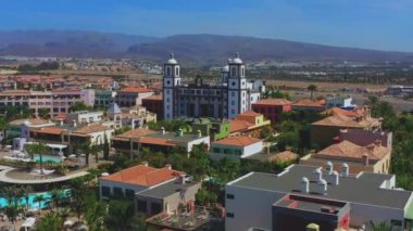 Lüks otellerin üzerinde uçmak, uzaktaki palmiyeleri ve dağları olan geniş tropikal bir ada keşfetmek. Özel Villalı Lüks Ada Tatil Köyü, Yüzme Havuzu, Tarif edilemez Deniz Manzarası.