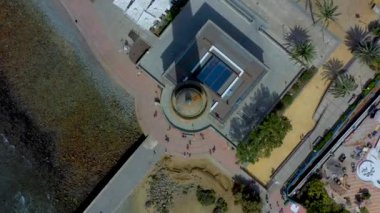 Kumsala yakın yüksek bir kulenin dönen hava manzarası. Sahildeki deniz fenerinin kuş manzarası. 4k Görüntü Tropikal Görünüm.