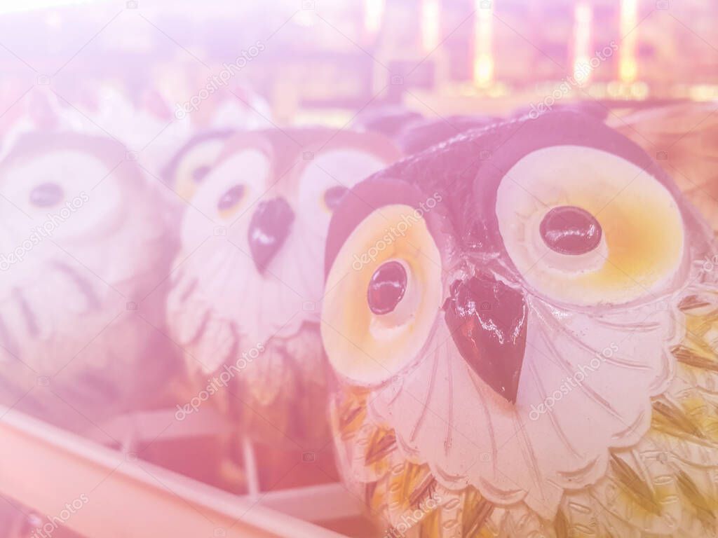 Stone owl toys soft blur background in pastel tones.