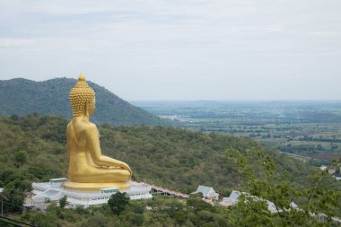 Gökyüzü arkaplanlı dağdaki altın Buda heykeli