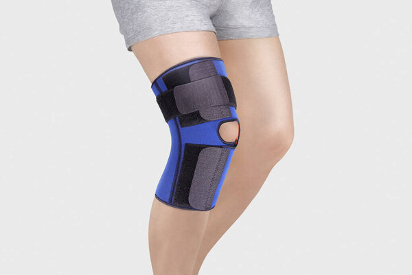 Knee Support Brace on leg isolated on white background. Orthopedic Anatomic Orthosis. Braces for knee fixation, injuries and pain. Orthotics. Foot orthosis. Knee Joint Bandage Sleeve. Elastic Sports 