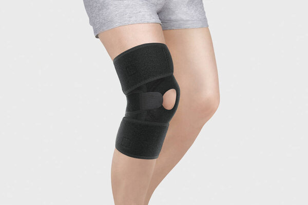 Knee Support Brace on leg isolated on white background. Orthopedic Anatomic Orthosis. Braces for knee fixation, injuries and pain. Orthotics. Foot orthosis. Knee Joint Bandage Sleeve. Elastic Sports 