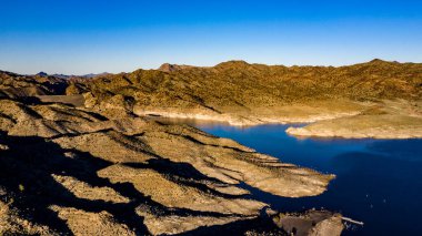 Arizona 'daki Alamo Gölü' nün insansız hava aracı görüntüsü Bill Williams Nehri üzerinde açık mavi gökyüzü ve su, kahverengi tepeler ve mor dağlar ve güzel çöl manzarası.
