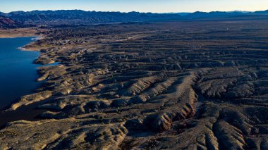 Arizona 'daki Alamo Gölü' nün insansız hava aracı görüntüsü Bill Williams Nehri üzerinde açık mavi gökyüzü ve su, kahverengi tepeler ve mor dağlar ve güzel çöl manzarası.