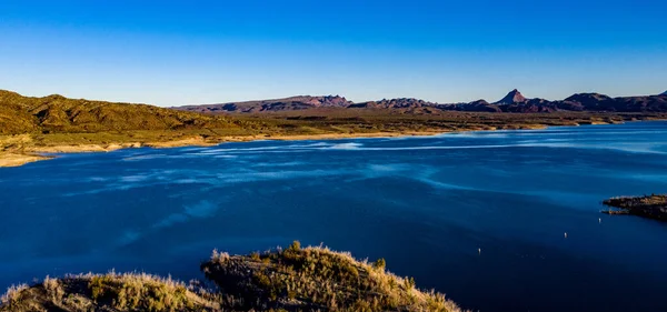 Arizona 'daki Alamo Gölü' nün insansız hava aracı görüntüsü Bill Williams Nehri üzerinde açık mavi gökyüzü ve su, kahverengi tepeler ve mor dağlar ve güzel çöl manzarası.
