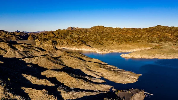 Arizona 'daki Alamo Gölü' nün insansız hava aracı görüntüsü Bill Williams Nehri üzerinde açık mavi gökyüzü ve su, kahverengi tepeler ve mor dağlar ve güzel çöl manzarası.