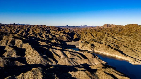 Arizona 'daki Alamo Gölü' nün insansız hava aracı görüntüsü Bill Williams Nehri üzerinde açık mavi gökyüzü ve su, kahverengi tepeler ve mor dağlar ve güzel çöl manzarası.
