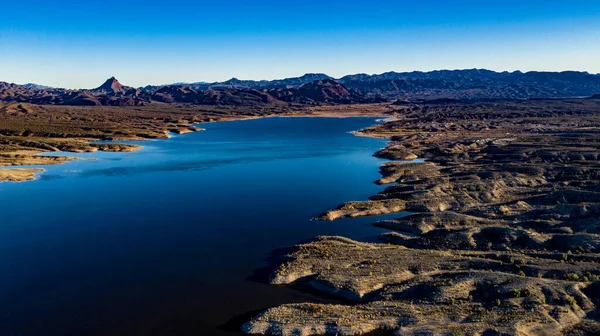 Arizona 'daki Alamo Gölü' nün insansız hava aracı görüntüsü Bill Williams Nehri üzerinde açık mavi gökyüzü ve su, kahverengi tepeler ve mor dağlar ve güzel çöl manzarası.