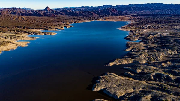 Arizona 'daki Alamo Gölü' nün insansız hava aracı görüntüsü Bill Williams Nehri üzerinde açık mavi gökyüzü ve su, kahverengi tepeler ve mor dağlar ve güzel çöl manzarası.