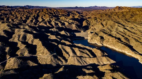 Arizona 'daki Alamo Gölü' nün insansız hava aracı görüntüsü Bill Williams Nehri üzerinde açık mavi gökyüzü ve su, kahverengi tepeler ve mor dağlar ve güzel çöl manzarası.