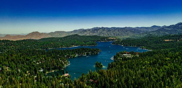 San Bernardino Dağları 'ndaki güzel Arrowhead Gölü' nün insansız hava aracı manzarası açık bir yaz gününde mavi su ve gökyüzü, yeşil orman çam ağaçları, mor tepeler ve dağlar