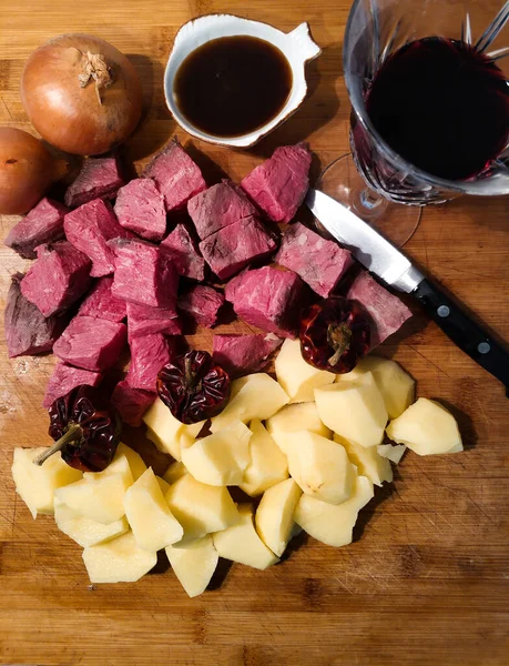 İyi ve farklı sığır güveci yapmak için malzemeler: patates, soğan, şarap ve biftek.