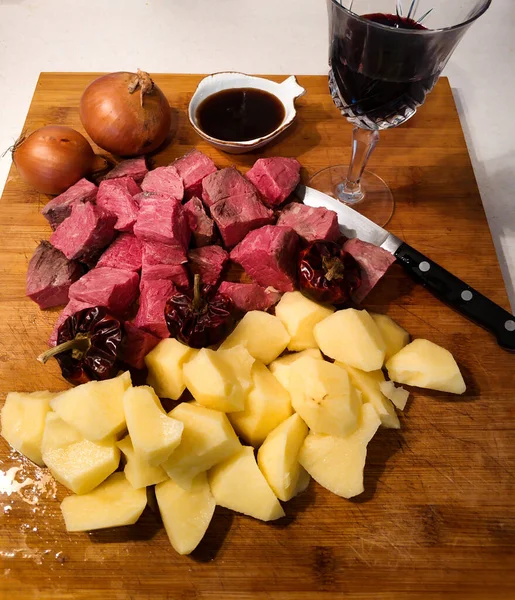 İyi ve farklı sığır güveci yapmak için malzemeler: patates, soğan, şarap ve biftek.