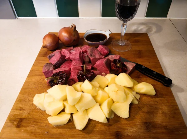 İyi ve farklı sığır güveci yapmak için malzemeler: patates, soğan, şarap ve biftek.