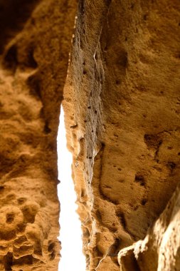 Büyük çatlaklarla bölünmüş ve güneş tarafından aydınlatılmış küçük bir kumtaşı mağarası. Kum taşı dokusu arkaplanı, doğal yüzey.