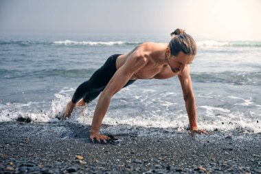 Egzersiz yap. Sağlıklı ve kaslı vücudu olan yakışıklı, aktif bir adamın şınav çekerken yakın çekimi. Spor Atletizm Erkek Egzersizi Sahilde, Açık havada Antrenman. Spor ve Spor Konsepti