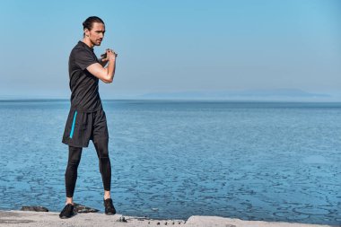 Genç kaslı sağlıklı yakışıklı aktif adam koşmadan önce geriniyor..