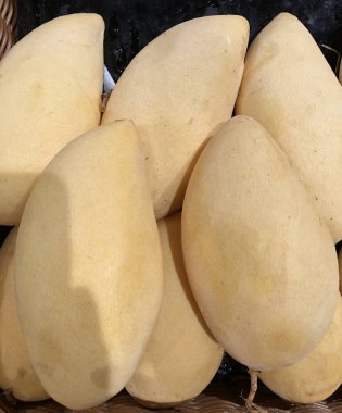 Süpermarketin tezgahında tropikal mango meyvesi var.