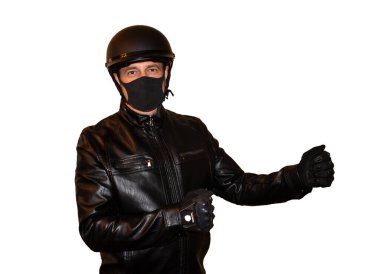 Beyaz arka plandaki motosikletli adamda kask ve koronavirüsten koruyan bir maske var. Siyah ceket, koruma ve motorcu eldivenleri.