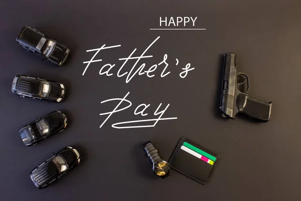 Holiday greeting card for Father\'s Day on a black background - the machine, gun, with the text - Happy Father\'s Day