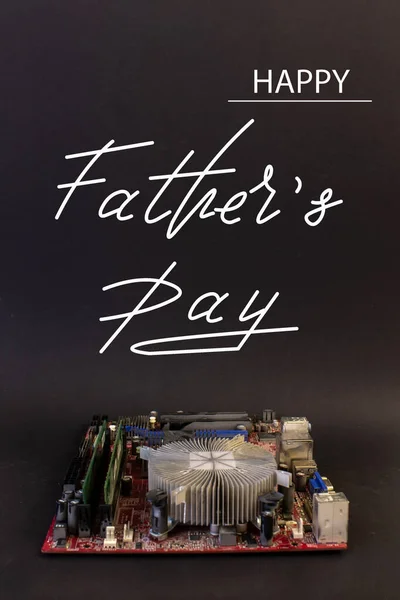 Holiday greeting card for Father\'s Day on a black background - machines, computer boards, with the text - Happy Father\'s Day
