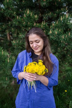 Kahverengi saçlı ve yeşil gözlü genç kız çiçek topluyor.