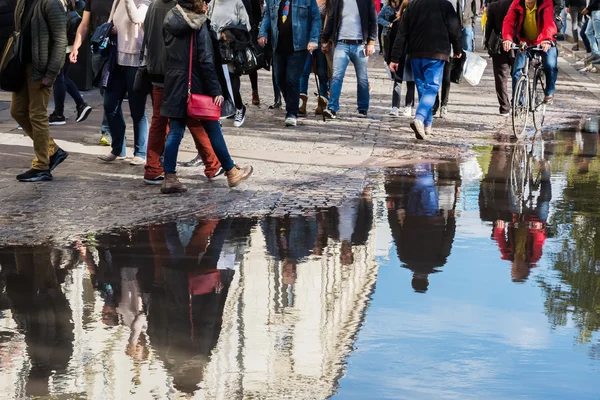 Skara människor som speglar sig i en vattenpöl — Stockfoto