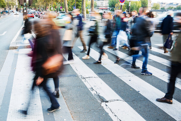 Толпа людей, переходящих городскую улицу
