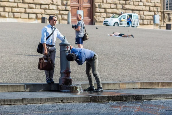 Businessmen drinking water at a drinking fountain at the Palazzo Pitti in Florence, Italy — Stock Photo, Image