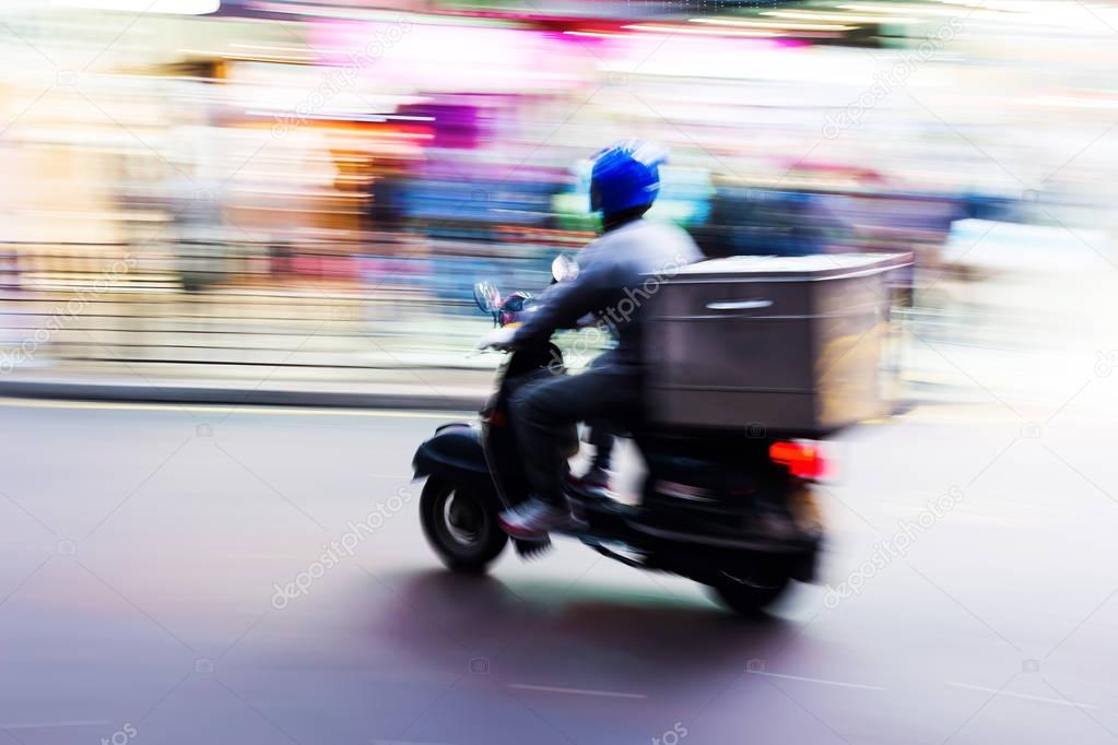 scooter messenger on the road in motion blur