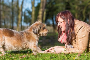 genç bir kadın ve köpeğini çim üzerinde yalan
