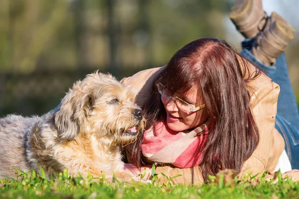 Jovem mulher encontra-se com seu cão na grama — Fotografia de Stock