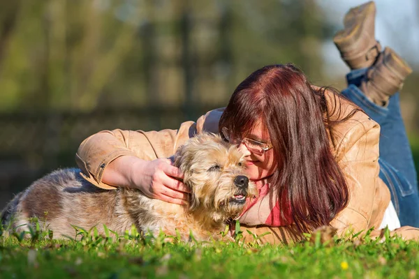 Jovem mulher encontra-se com seu cão na grama — Fotografia de Stock