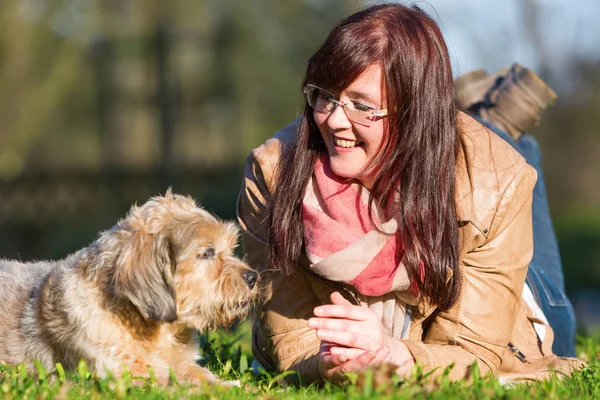 Jovem mulher encontra-se com seu cão na grama — Fotografia de Stock