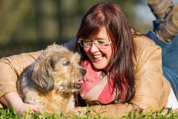 Jovem mulher encontra-se com seu cão na grama — Fotografia de Stock