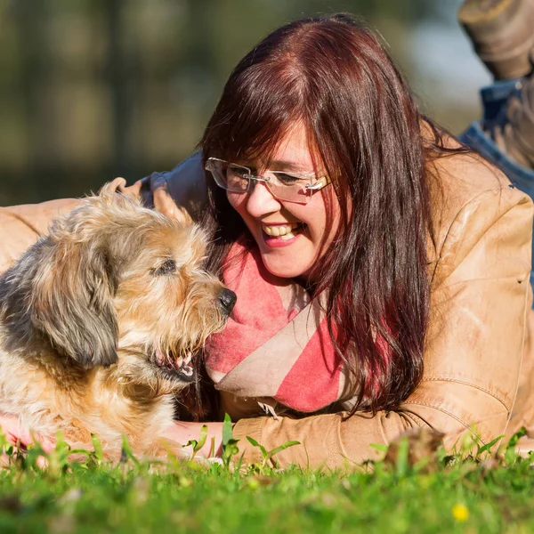 Jovem mulher encontra-se com seu cão na grama — Fotografia de Stock