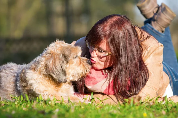 Young woman lies with her dog in the grass — Stock Photo, Image