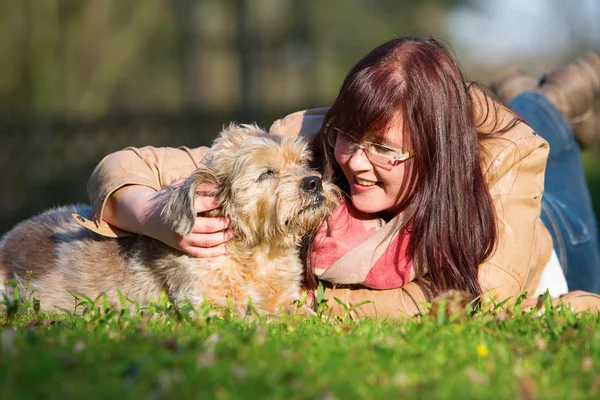 Jovem mulher encontra-se com seu cão na grama — Fotografia de Stock