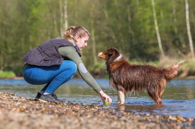 genç kadın nehirde bir köpekle oynamayı