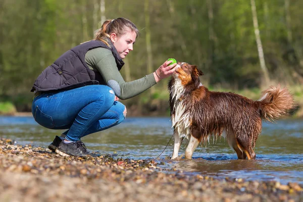 Junge Frau spielt mit Hund am Fluss — Stockfoto